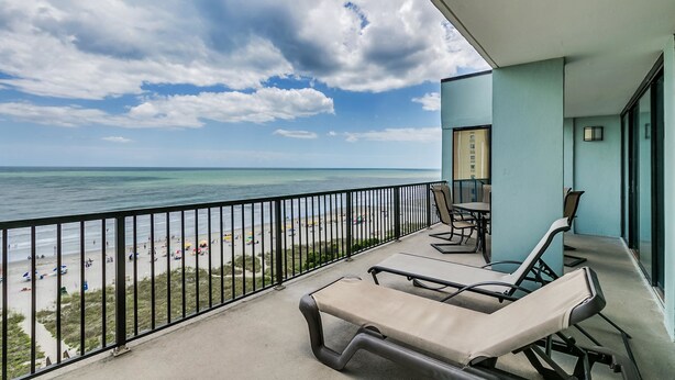 A balcony with lounge chairs overlooking a beach and ocean. - Carolina Dunes 304 2 Bedroom Condo by Luxury (Myrtle Beach)