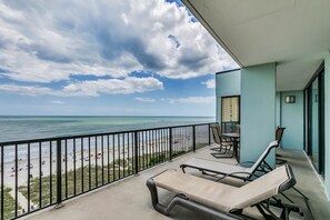 A balcony with lounge chairs overlooking a beach and ocean. - Carolina Dunes 304 2 Bedroom Condo by Luxury (Myrtle Beach)