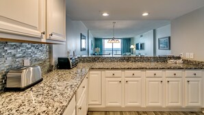 A modern kitchen with white cabinets, granite countertops, and a built-in toaster. - Carolina Dunes 304 2 Bedroom Condo by Luxury (Myrtle Beach)