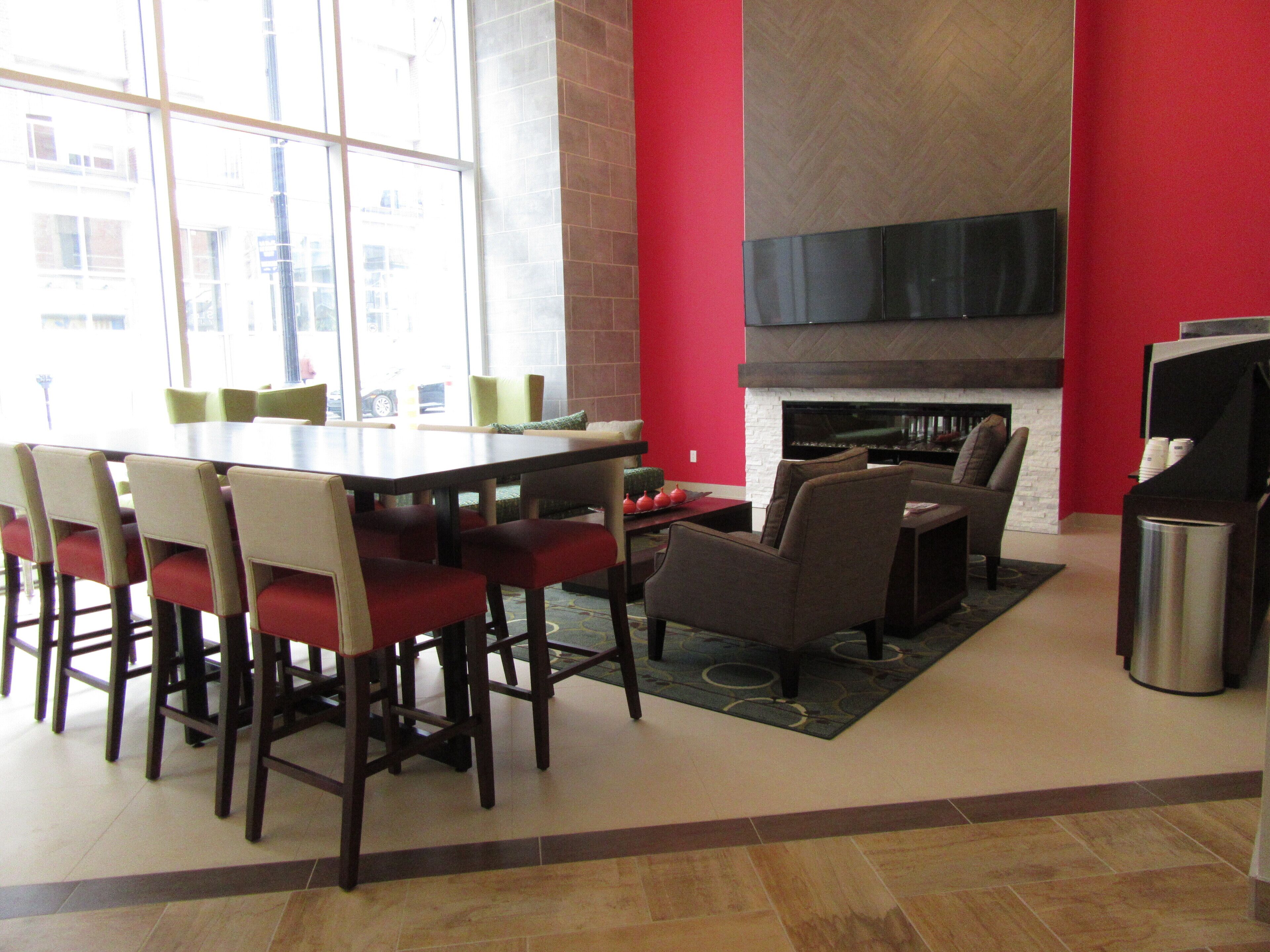 Uma sala de jantar moderna com uma mesa grande e cadeiras, uma lareira e uma televisão.