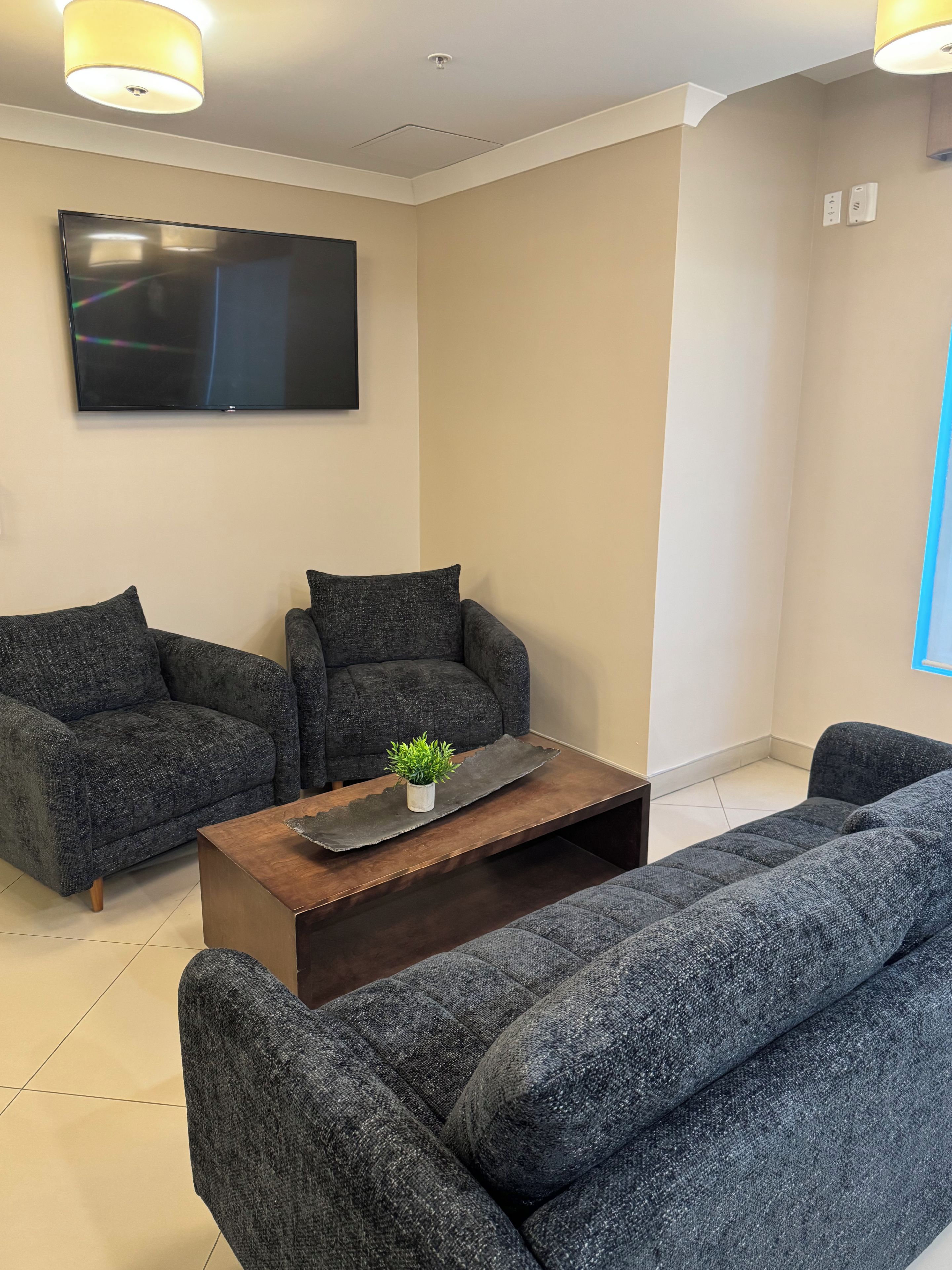 A living room with two grey sofas, a wooden coffee table, and a flat-screen TV mounted on the wall.