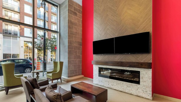 A modern lounge area with a fireplace, comfortable seating, and a large window offering a view of the street.