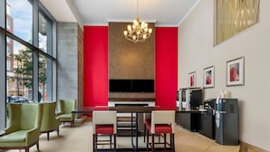 A modern kitchen with a large dining table, green chairs, a chandelier, and a coffee machine.