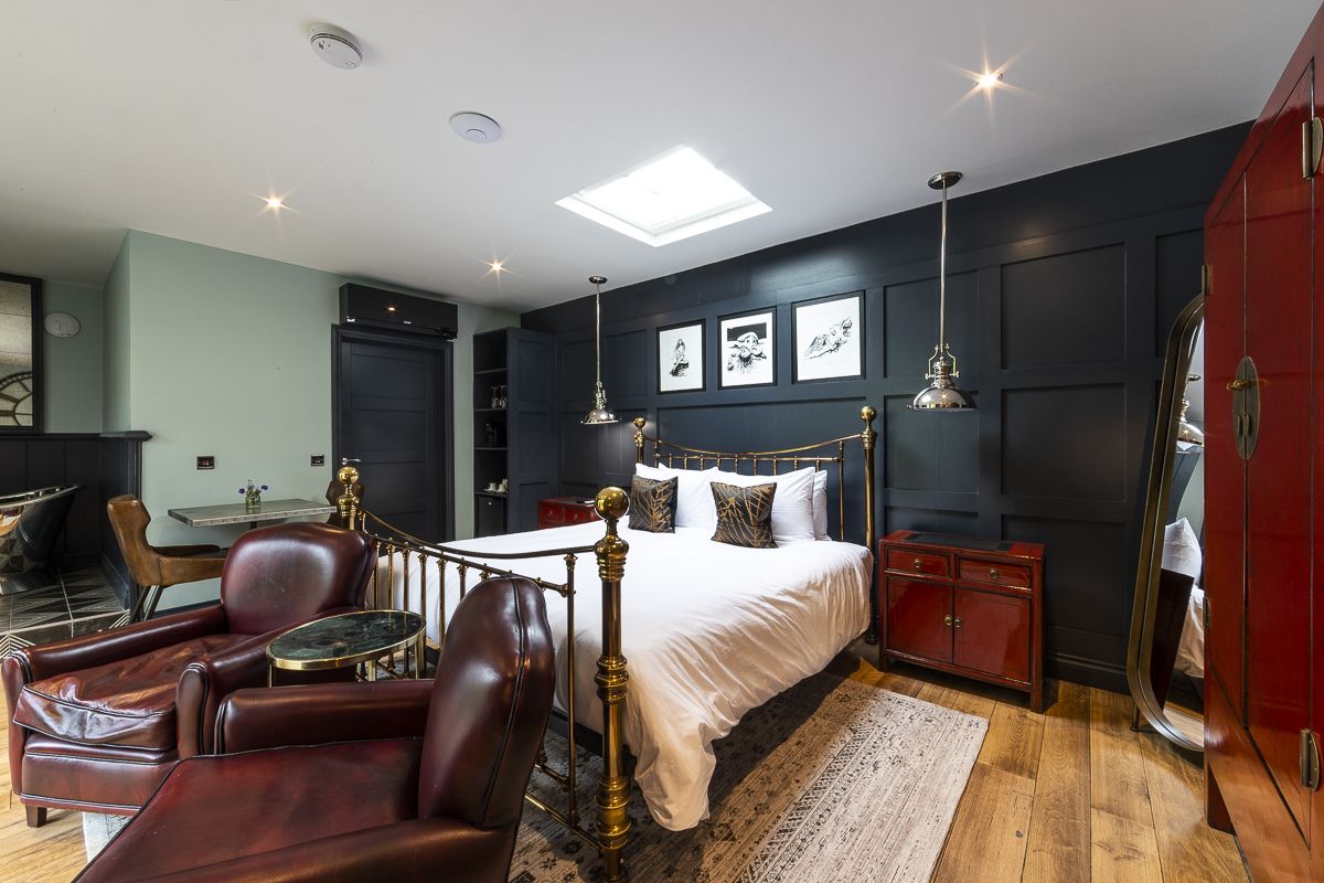 A bedroom with a large bed, a desk, a chair, and a wardrobe.
