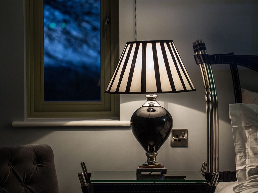 A lamp with a striped lampshade on a bedside table.