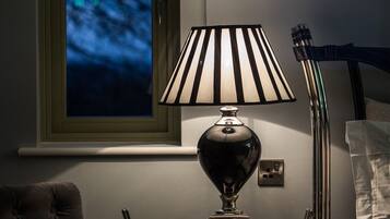 A lamp with a striped lampshade on a bedside table.