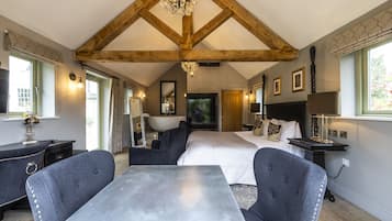 A spacious bedroom with a large bed, a dining table, and a chandelier.