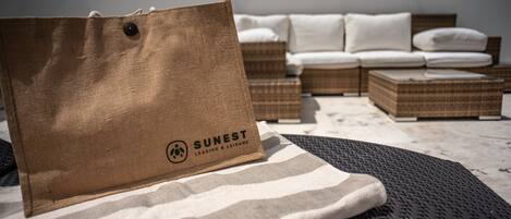 Un sac en papier brun sur lequel est imprimé le texte « SUNEST LEASING & LEISURE », posé sur un tissu à rayures sur une chaise en osier.