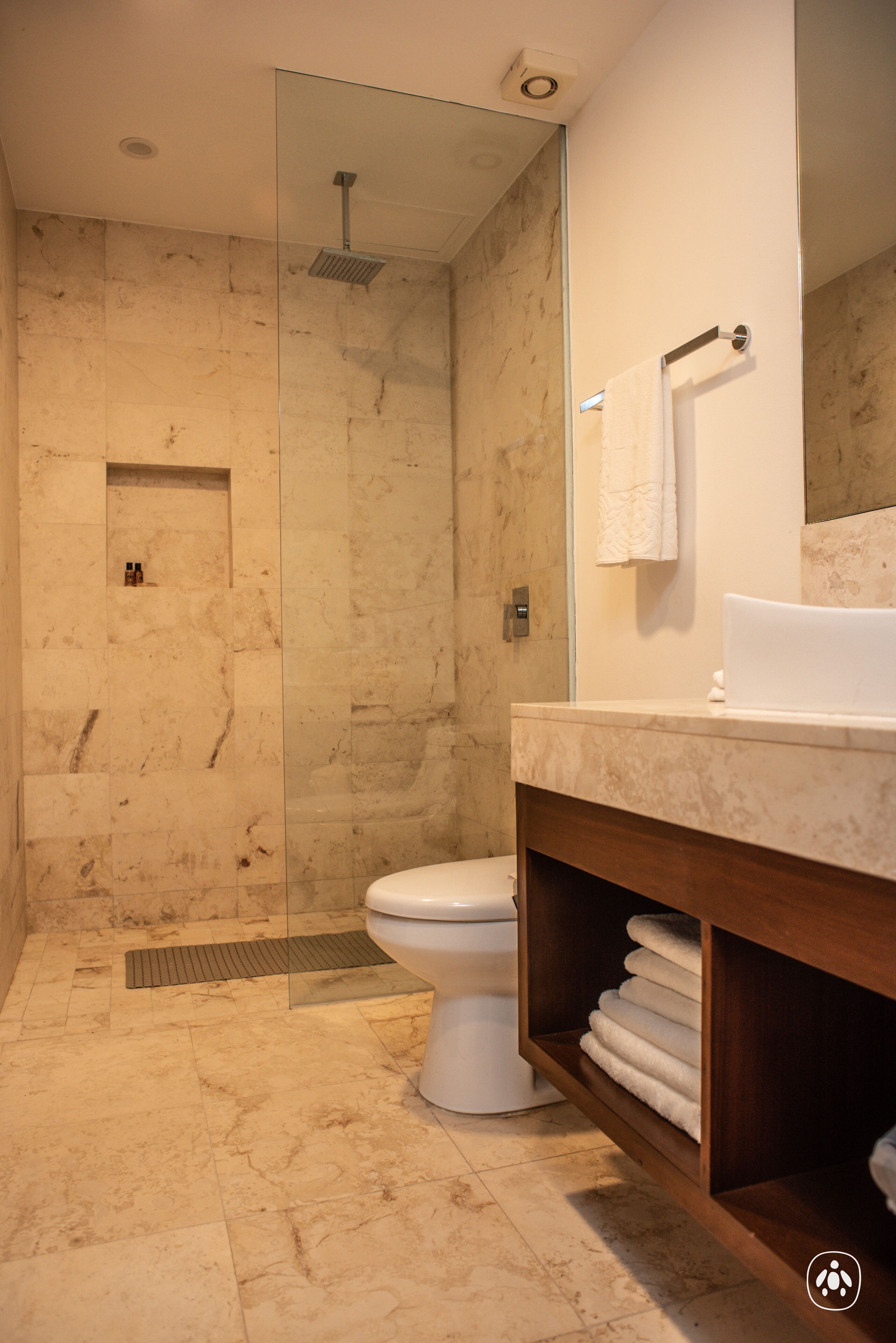 A modern bathroom with a glass-enclosed shower, a white toilet, and a marble sink.