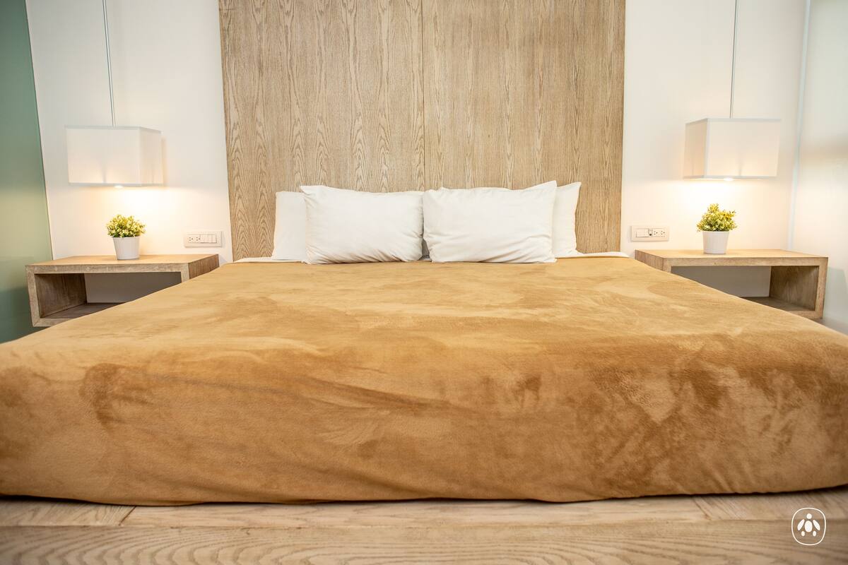A large bed with a brown cover, two bedside tables with lamps, and a wooden headboard.