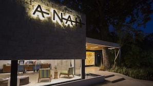 Un edificio moderno con un letrero visible que dice 'NA+', una recepción y una zona de estar con sillas y una mesa.