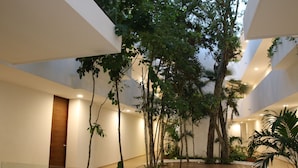 Un amplio atrio interior con techos altos, piso de madera y una variedad de plantas de interior.