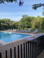 Una piscina al aire libre, sombrillas, sillones reclinables de piscina