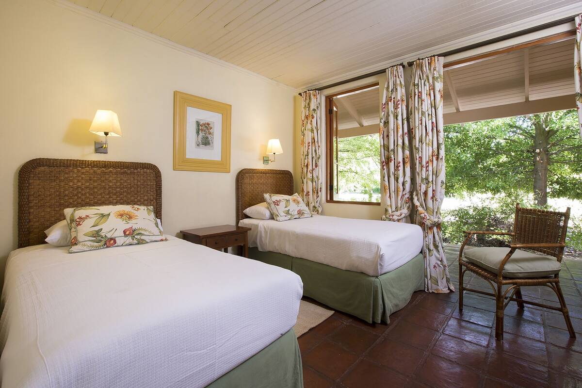 Una habitación con dos camas, una silla y una ventana con cortinas.