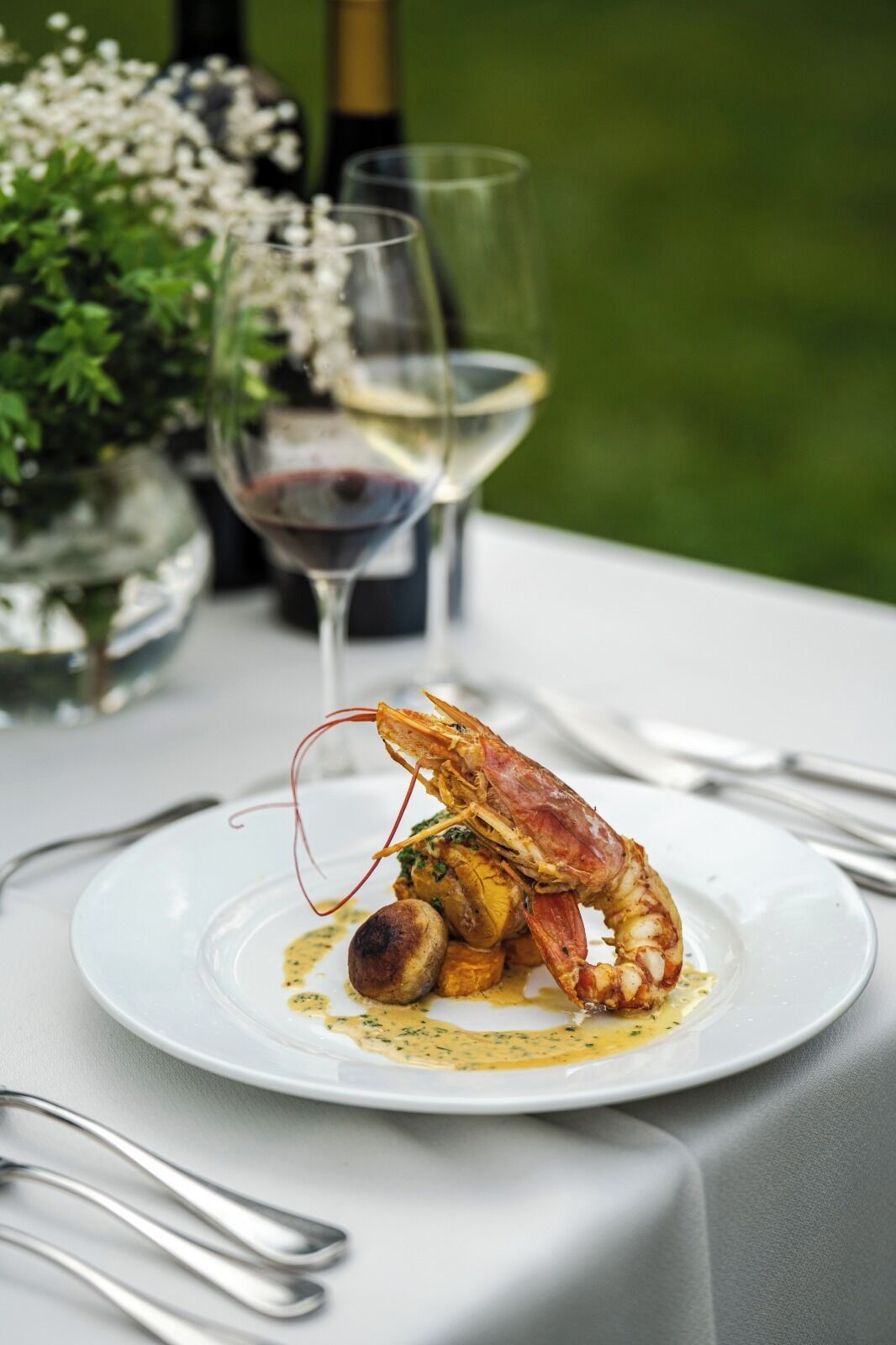 Une table à manger avec une assiette de nourriture, un verre de vin et une bouteille de vin.