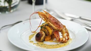Une table à manger avec une assiette de nourriture, un verre de vin et une bouteille de vin.