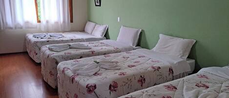 A hotel room with four beds, each with floral bedding and towels neatly arranged.