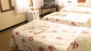 Una habitación de hotel con dos camas, televisión, un refrigerador pequeño y una ventana con cortinas.