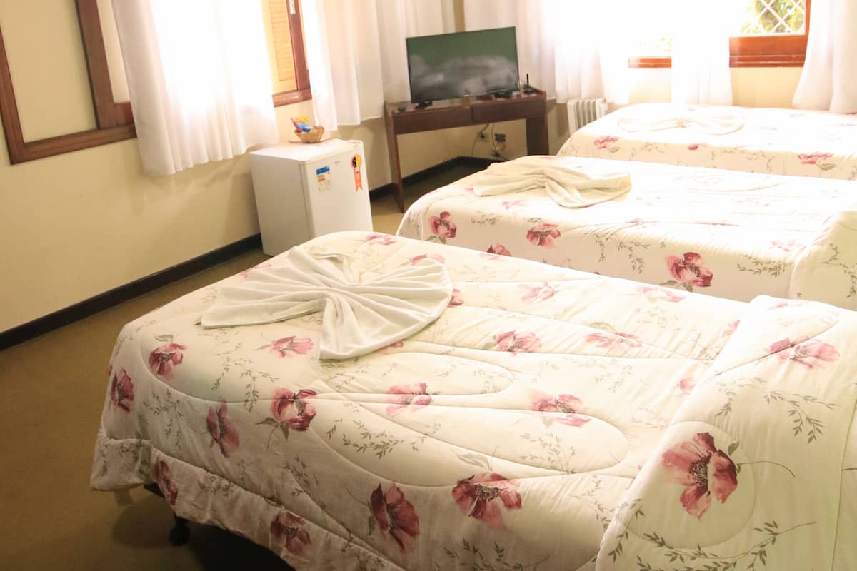 Ein Hotelzimmer mit zwei Betten, einem Fernseher, einem kleinen Kühlschrank und einem Fenster mit Vorhängen.