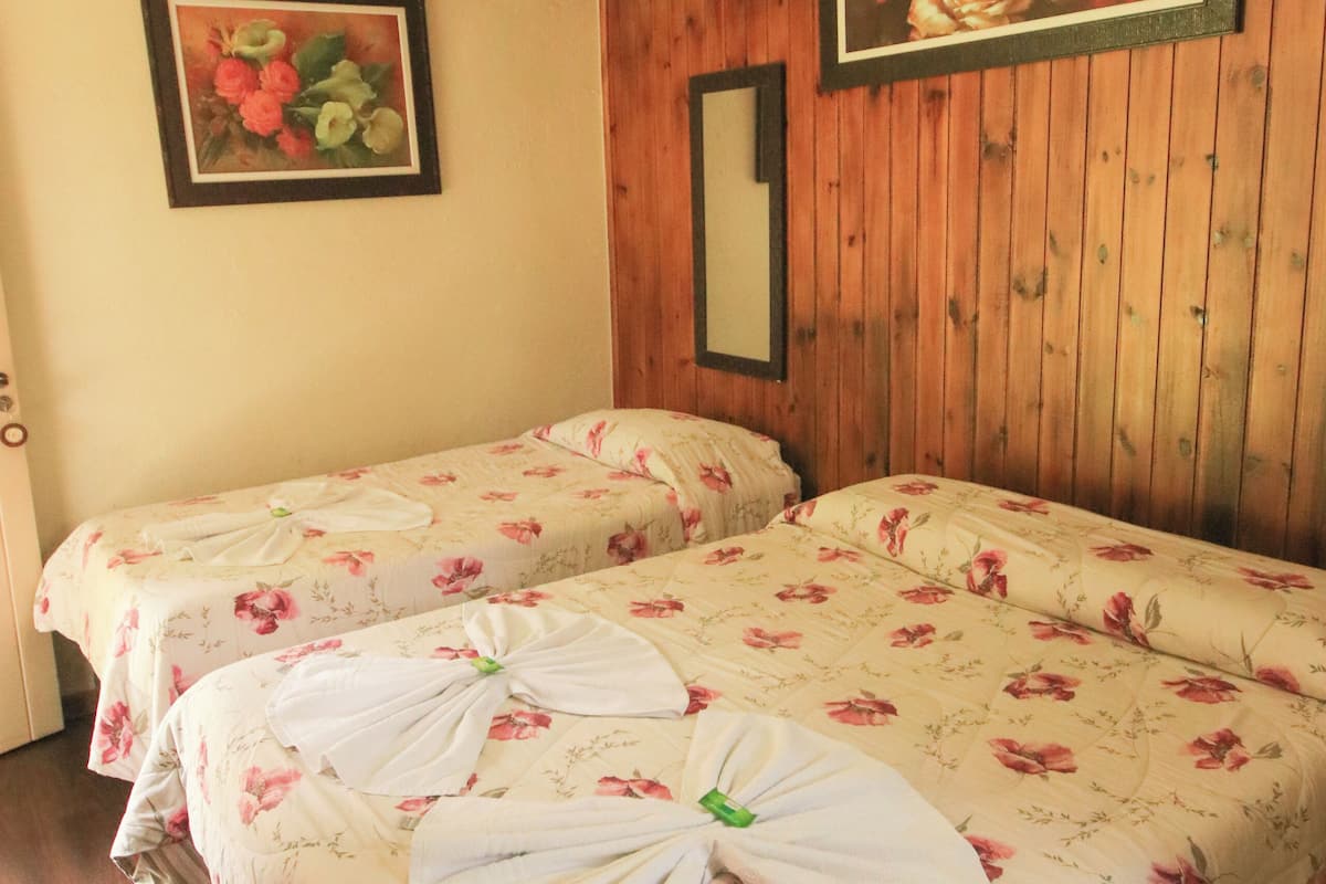 Ein Zimmer mit zwei Betten, Holzvertäfelung an den Wänden und blumigem Bettzeug.