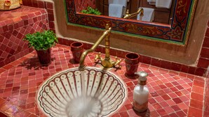 A bathroom with a red tiled sink, a brass faucet, and a mirror with a decorative frame. - Les Sources Berbères Riad & Spa (Marrakech)