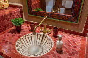 A bathroom with a red tiled sink, a brass faucet, and a mirror with a decorative frame. - Les Sources Berbères Riad & Spa (Marrakech)