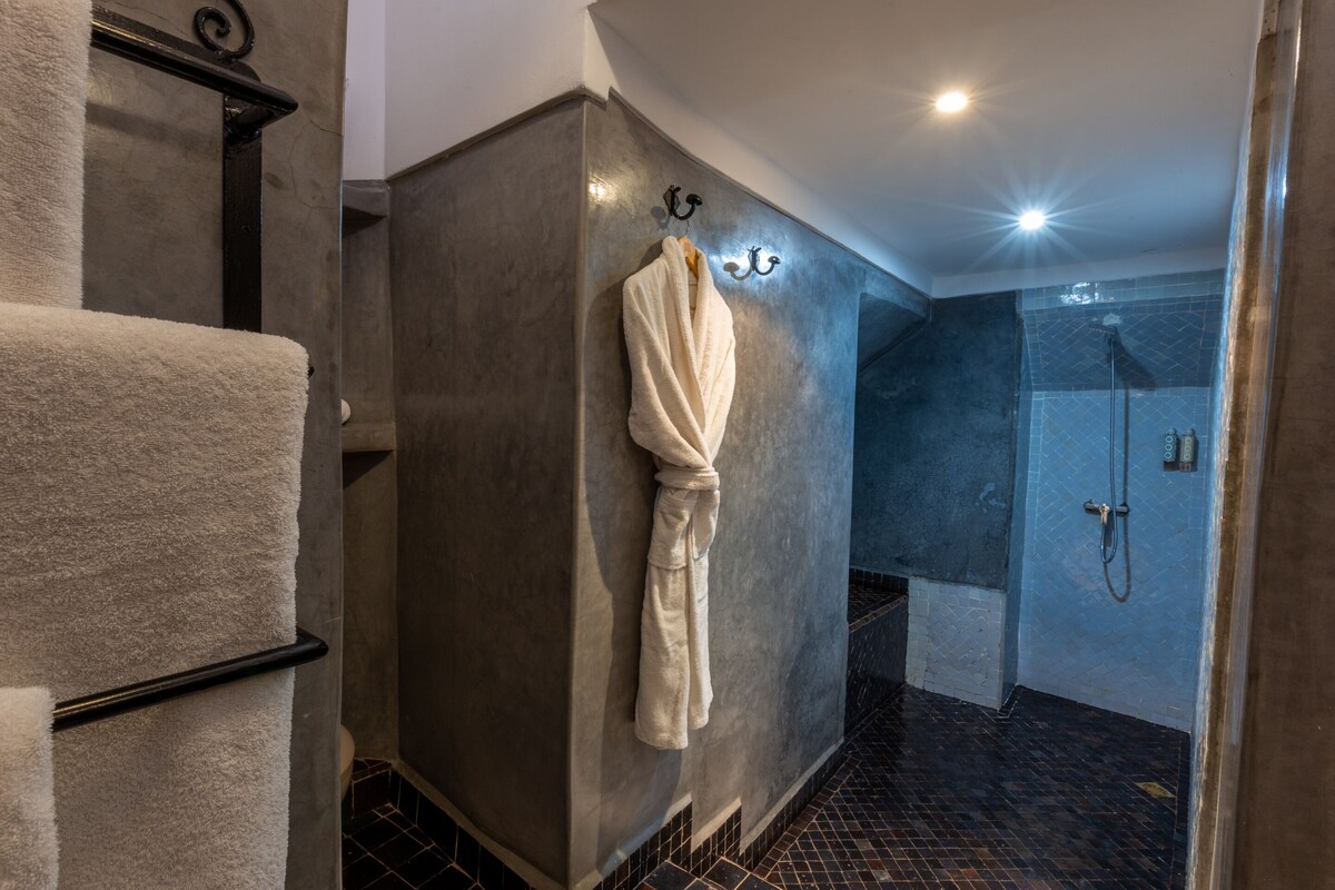 A bathroom with a towel rack, a shower area, and a tiled floor.