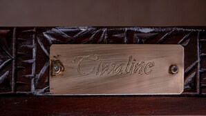 A wooden plaque with the name 'Catherine' engraved on it, mounted on a dark wooden surface with a geometric pattern. - Les Sources Berbères Riad & Spa (Marrakech)