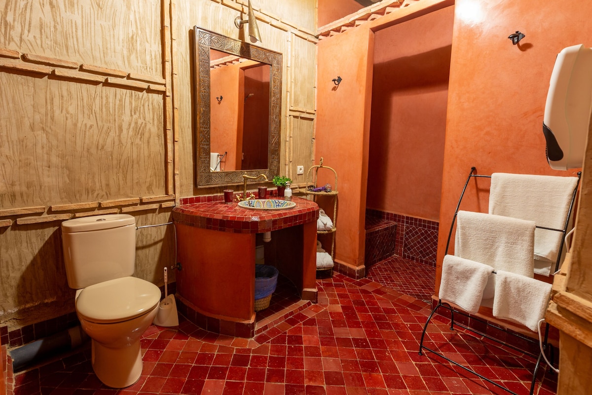 A bathroom with a toilet, sink, mirror, and towel rack.