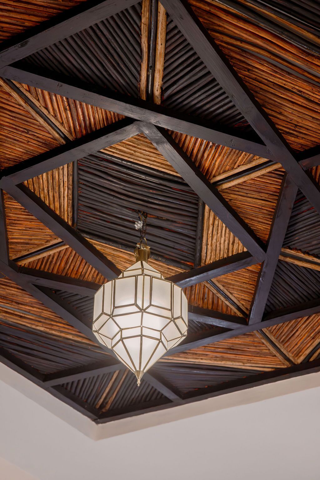Een geometrisch plafondontwerp met een hanglamp in het midden.