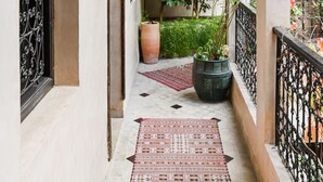 A corridor with a patterned rug, a potted plant, and a hanging light fixture. - Les Sources Berbères Riad & Spa (Marrakech)