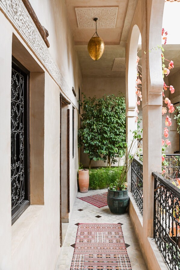 A corridor with a patterned rug, a potted plant, and a hanging light fixture. - Les Sources Berbères Riad & Spa (Marrakech)
