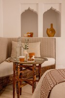 A cozy seating area with a patterned sofa, a small wooden table with a glass pitcher, a cup, and a plate of cookies.