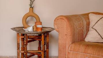 A wooden table with a vase and a cup, a patterned sofa, and a plain wall.