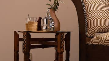 A wooden table with a woven basket and a metal pitcher, placed next to a patterned sofa.