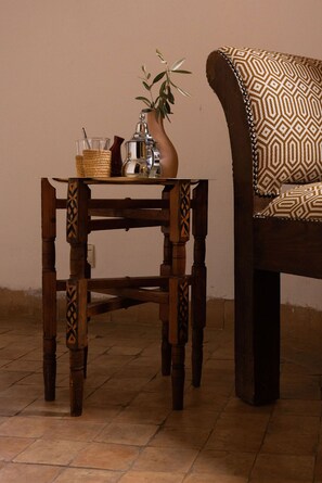 A wooden table with a woven basket and a metal pitcher, placed next to a patterned sofa. - Les Sources Berbères Riad & Spa (Marrakech)