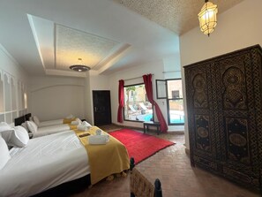 A hotel room with two beds, a red carpet, a pool view, and a traditional door. - Les Sources Berbères Riad & Spa (Marrakech)