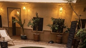A pool with a geometric design, surrounded by potted plants and a lounge area with a chair and a table. - Les Sources Berbères Riad & Spa (Marrakech)