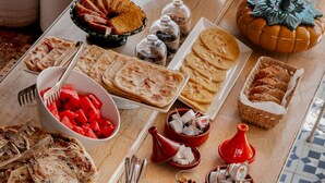 A table with various food items and drinks, including flatbreads, pastries, and a decorative pumpkin. - Les Sources Berbères Riad & Spa (Marrakech)