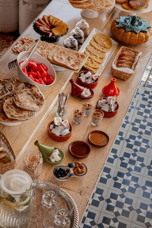 A table with various food items and drinks, including flatbreads, pastries, and a decorative pumpkin. - Les Sources Berbères Riad & Spa (Marrakech)