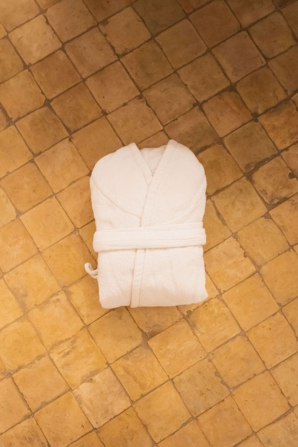 A white bathrobe on a tiled floor.