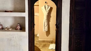 A room with a doorway leading to another space, shelves with decorative items, and a dark wooden door. - Les Sources Berbères Riad & Spa (Marrakech)