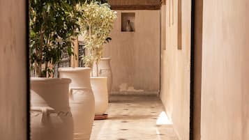 Un couloir étroit, orné de grands pots en terre cuite, doté d’un sol carrelé et d’une arche décorative.