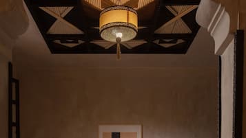 Una habitación de hotel con una cama, una silla, una mesa con una bandeja de objetos y un cuadro en la pared.