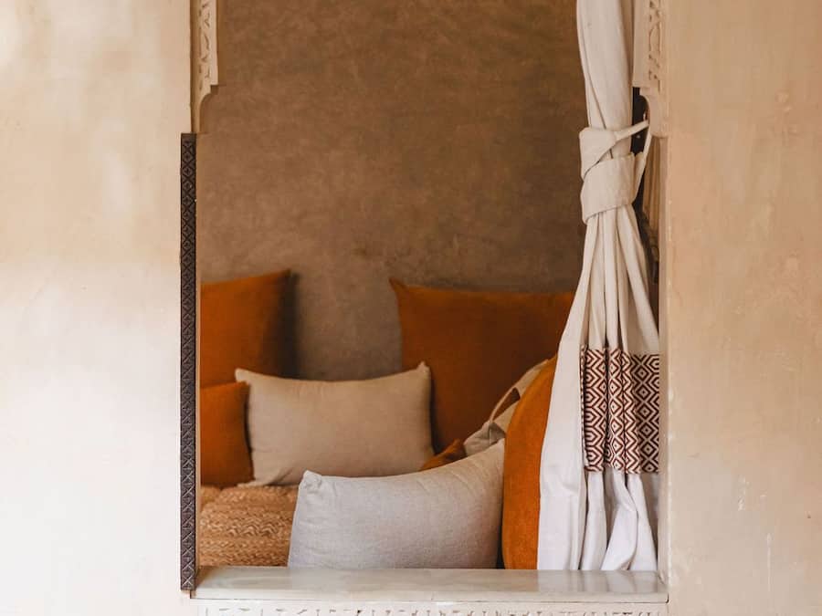 A cozy room with a decorative archway, a hanging light fixture, and a bed with pillows.