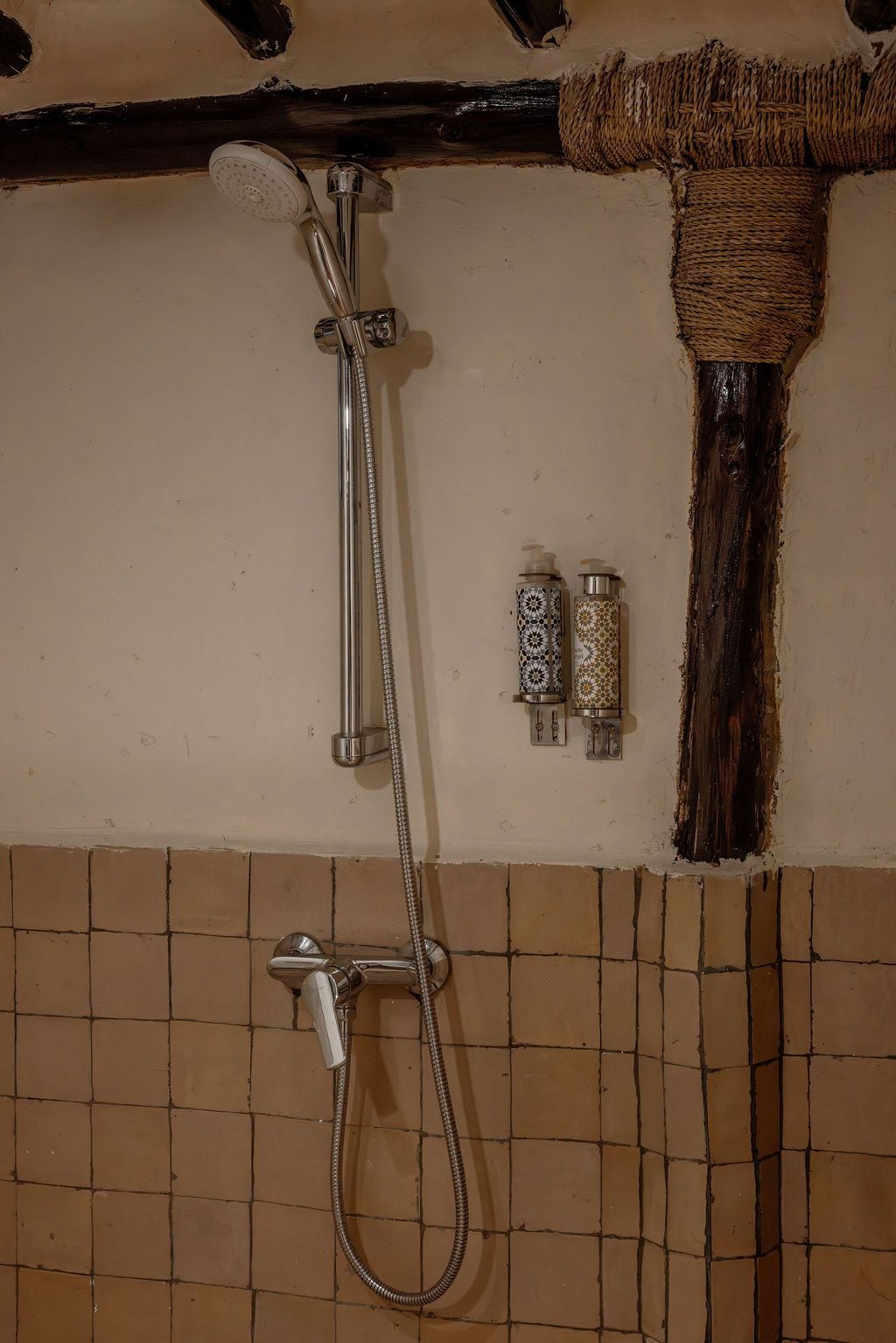 A shower with a handheld showerhead and a wall-mounted faucet.