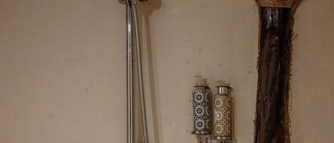 A shower with a handheld showerhead and a wall-mounted faucet.