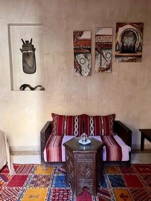 A room with a sofa, a small table, and a patterned rug. - Les Sources Berbères Riad & Spa (Marrakech)