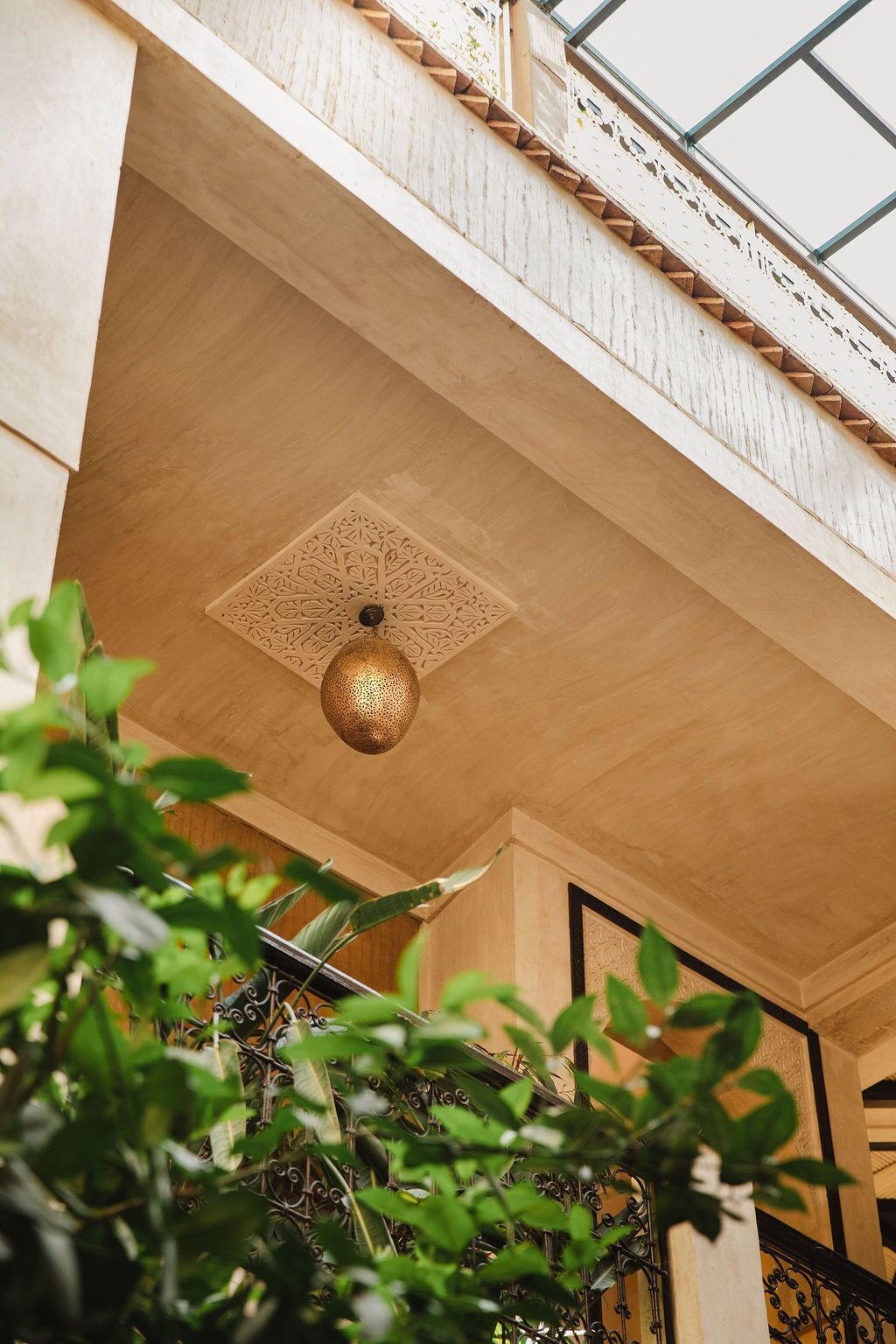 A room with a wooden ceiling, a decorative ceiling light fixture, and a view of the outdoors through a window.