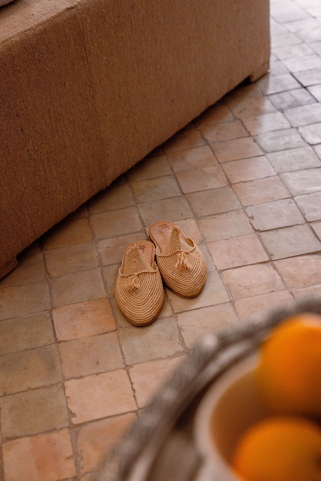 A pair of woven slippers on a tiled floor.